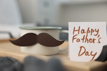 Happy Father's Day card and cup with mustache on bed at home, closeup
