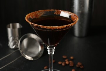 Martini cocktail with sugar in glass and coffee beans on black table, closeup