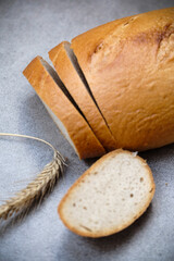 A freshly sliced sourdough bread on a table with ear of wheat
