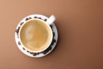 Cup of hot coffee on brown background, top view. Space for text