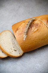 A freshly sliced sourdough bread on a table with ear of wheat
