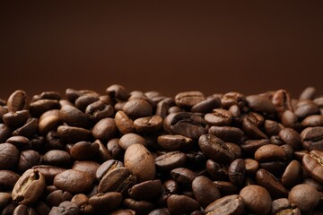 Pile of roasted coffee beans on brown background, closeup