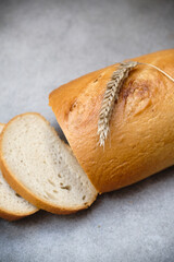 A freshly sliced sourdough bread on a table with ear of wheat