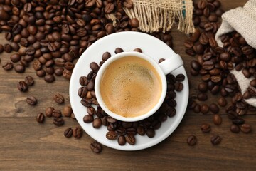 Aromatic coffee in cup and beans on wooden table, flat lay