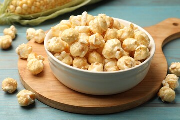 Tasty popcorn and corncob on light blue wooden table, closeup