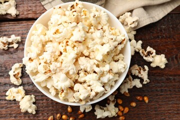 Tasty popcorn and corn kernels on wooden table, flat lay