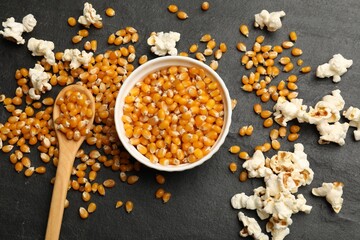 Corn kernels and tasty popcorn on black table, flat lay
