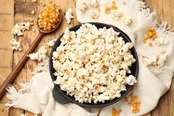 Tasty popcorn and corn kernels on wooden table, flat lay