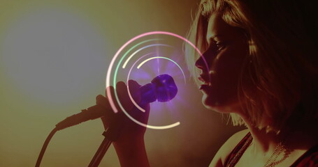 Singing singer performing with handheld microphone and circular overlay on dark stage, copy space