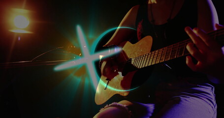 Strumming guitarist in tank top on stage, with acoustic guitar, mic stand, spotlight, blue light