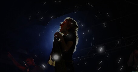 Singing backlit singer holding microphone stand on music venue stage, with fog and metal trusses