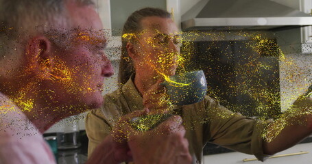 Senior couple tasting hot drink in bright home kitchen, with ceramic mugs and golden particles