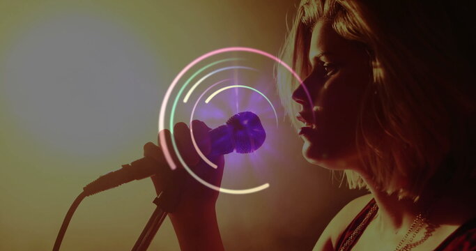 Singing singer performing with handheld microphone and circular overlay on dark stage, copy space