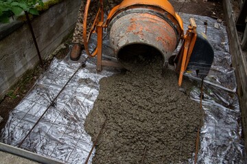 Liquid concrete pours out of a small concrete mixer