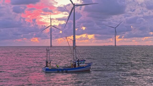 Colorful sunset above Wadden Sea, aerial with trawler and windfarm