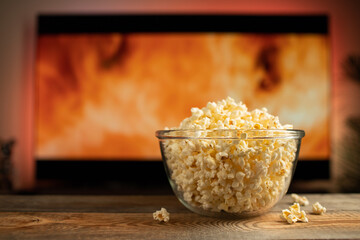 A glass bowl of popcorn and remote control in the background the TV works