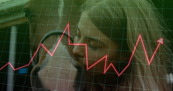 Pressing cheek against horse muzzle at farmyard, wearing winter jacket with grid and chart overlay