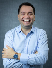 Happy businessman with crossed arms, wearing blue shirt, laughing and looking at camera. Perfect for corporate business, career promotion, office work, manager or CEO. Studio portrait with copy space.