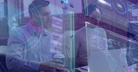 Analyzing colleagues reviewing data charts at conference room desk, with laptop and coffee cup