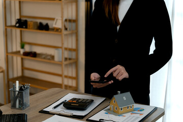 Adult real estate agent analyzing property finance data with smartphone calculating investments planning home purchase business at office desk
