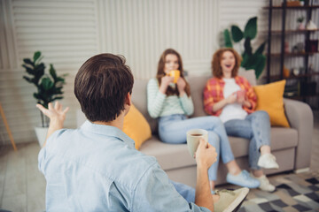 Fototapeta premium Funny young friends enjoying casual conversation in a vibrant living room, sharing laughter during a relaxing sunny weekend