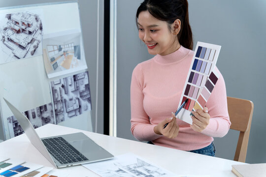 Asian woman architect interior designer discussing color palette online meeting presentation remote work home office studio desk