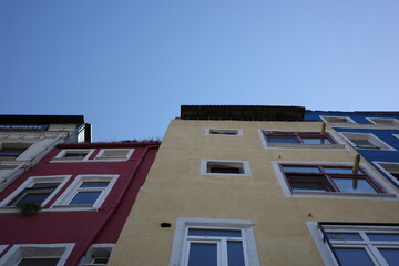 Colorful red, yellow and blue old town buildings with windows under clear blue sky