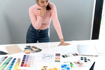 Asian woman architect designer plans creative home interior decoration project using color palettes blueprints thinking ideas