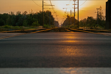 Railroad crossing with a road for cars, yellow sunset