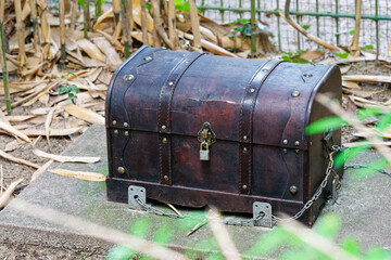Old travel trunk treasure chest with straps fixed by chains on concrete