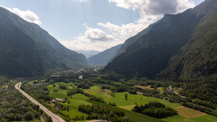 Aerial view of the Valsugana highway crossing the green valley surrounded by mountains in Grigno, Trentino, Italy