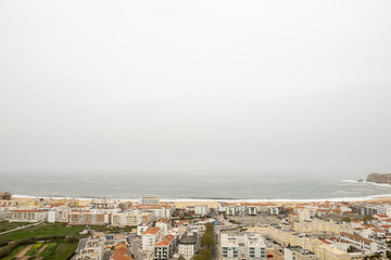 Nazare coastal settlement revealing dramatic Portuguese shoreline, gray skies casting moody...