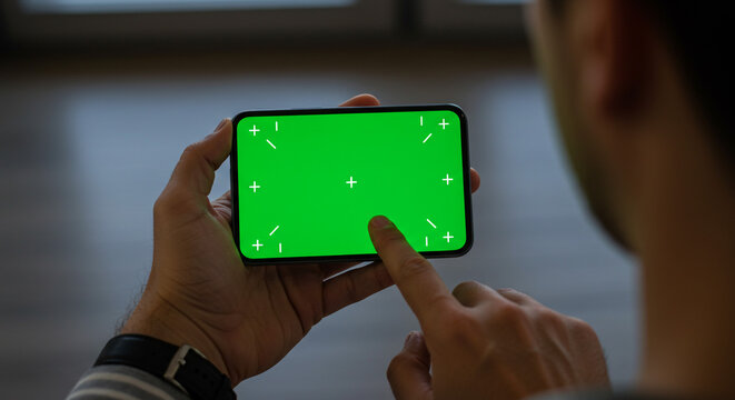 Person using a smartphone with a green screen, perfect for custom content creation and digital design projects - Powered by Adobe