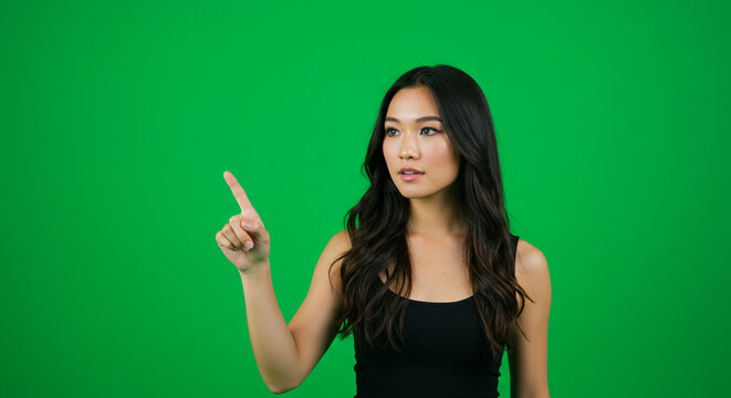 Confident businesswoman points to future opportunities on a vibrant green screen background