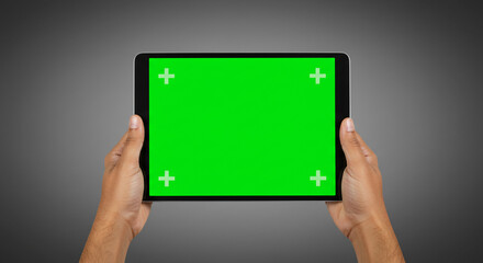 Hands holding tablet with green screen for custom content creation and digital display