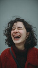 The joyful woman with curly hair bursts into laughter, exuding pure happiness and fun in this candid portrait.