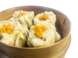 Traditional steamed dim sum dumplings in a bamboo basket isolated on a white background. Asian cuisine, Chinese food concept.