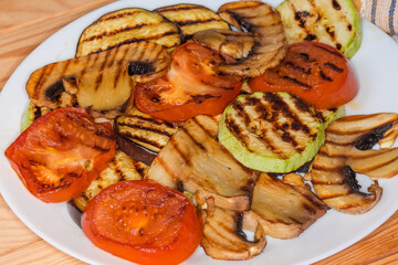 Grilled sliced mushroom and vegetables on plate on wooden table