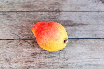Ripe red-yellow pear lies on an old wooden surface outdoors
