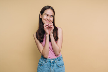 Young woman smiling playfully against a neutral background, expressing joy and confidence in a...