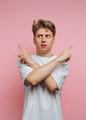 Young man gestures with confusion against a pink background during a playful photoshoot