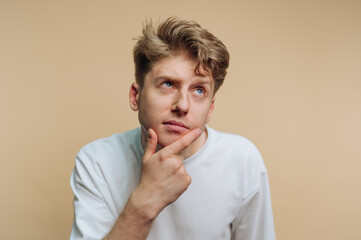 Young man contemplates ideas against a neutral backdrop in a casual setting