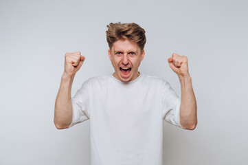Excited man celebrates victory with raised fists in a bright studio setting