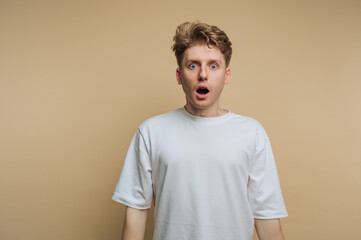 Surprise expression on a young man with light brown hair against a neutral background