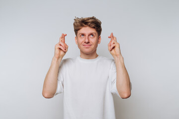 Man showing crossed fingers for good luck in a neutral setting with a cheerful expression during...