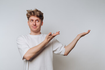 Man gestures with hands while looking thoughtfully to the side in a minimalist indoor setting