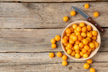 Ripe yellow cherry plums and knife on wooden table, flat lay. Space for text