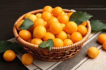 Ripe yellow cherry plums and leaves on dark wooden table, closeup