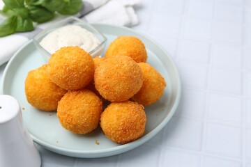 Delicious fried croquette balls and sauce on light tiled table, closeup