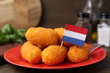 Delicious fried croquettes and flag of Netherlands on table, closeup